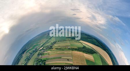 Vista aerea dall'alta quota del piccolo pianeta terra con campi agricoli verdi e gialli coltivati con colture in crescita in luminoso giorno d'estate Foto Stock