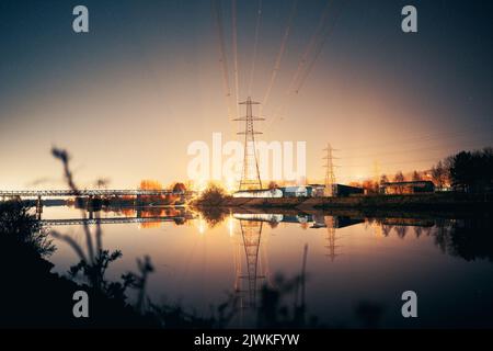 Newburn UK: 6th marzo 2022: Newburn Riverside di notte tralicci elettrici, club di canottaggio e ancora fiume con luce industriale calda e luminosa Foto Stock