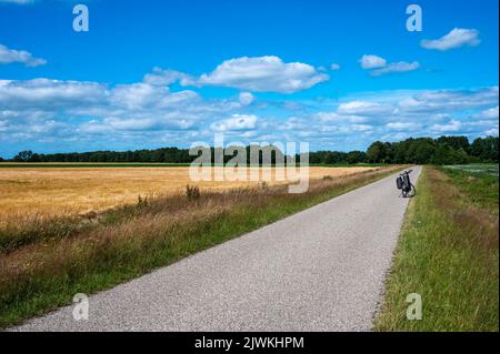 Norg, Drenthe, Paesi Bassi, 07 20 2022 - strada attraverso i campi verde e giallo e verde sopra il cielo blu nella campagna olandese Foto Stock