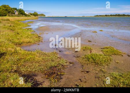 Vista lungo la baia fino al vecchio scafo in legno di un relitto sulla riva lontana. Traeth Dulas, Isola di Anglesey, Galles del Nord, Regno Unito, Gran Bretagna, Europa Foto Stock