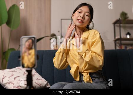 Asian Beauty Blogger Donna fare Massaggio facciale creare Video Indoor Foto Stock
