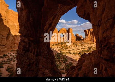 Il lato posteriore del Double Arch incorniciato da Cove Arch nell'area di Cove of Caves del Parco Nazionale di Arches, Moab, Utah. Foto Stock