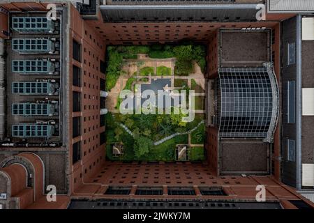 Una vista aerea direttamente sopra un giardino cortile interno appartato nel centro di un condominio cittadino circondato da mura di mattoni rossi Foto Stock