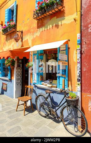 ISOLA DI BURANO, VENEZIA, ITALIA - 4 LUGLIO 2022: Biciclette parcheggiate di fronte ad un negozio di souvenir dai colori vivaci. Case colorate nell'Isola di Burano. Famoso tr Foto Stock