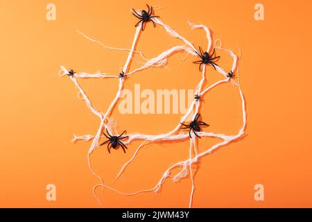 Giocattoli multipli del ragno che formano una ragnatela del ragno con lo spazio della copia contro lo sfondo arancione Foto Stock