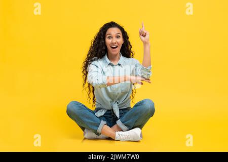 Excited Female che ha idea che punta il dito su su sfondo giallo Foto Stock
