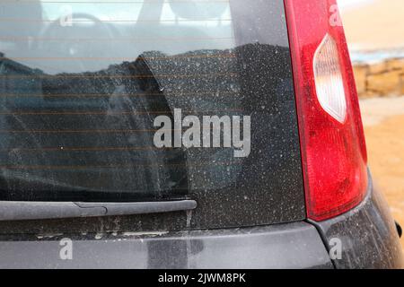 L'auto sporca ha bisogno di un lavaggio. Piccola vettura con sporco sul parabrezza posteriore. Foto Stock