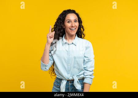 Donna allegra che punta il dito su avere idea, sfondo giallo Foto Stock