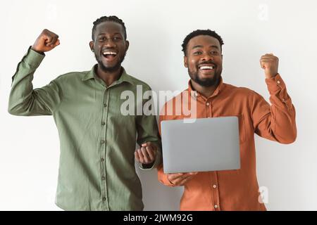 Due afro-americani che tiene portatile Shaking Fists, sfondo bianco Foto Stock