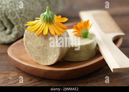 Pezzi di shampoo naturale organico calendula, fiori di calendula, pettine di legno per capelli e asciugamano. Messa a fuoco selettiva. Foto Stock