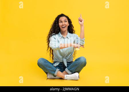 Donna araba eccitata che punta il dito su avere idea, sfondo giallo Foto Stock