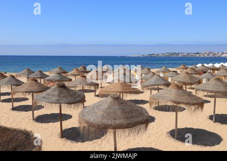 Estoril, Portogallo - spiaggia di Tamariz sabbia e ombrelloni di paglia. Foto Stock