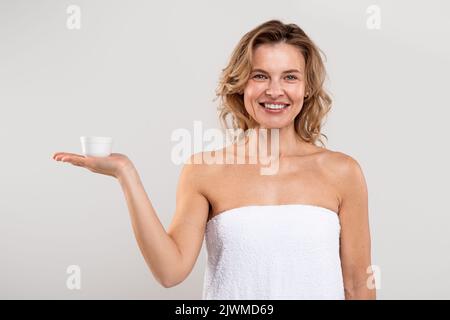 Cosmetici anti-Age. Bel vaso di sostegno femminile di mezza età con crema sul palmo Foto Stock