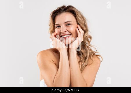 Positiva bella donna di mezza età che posa su sfondo grigio chiaro Foto Stock