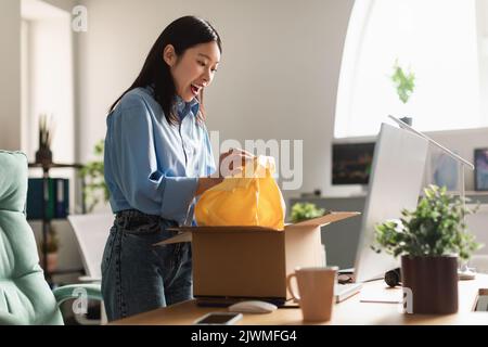 Joyful coreano femmina Unpacking Box ricezione di pacchi consegnati a casa Foto Stock