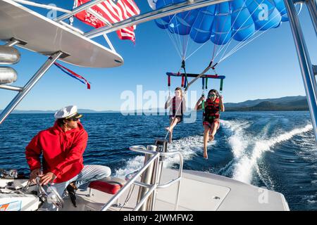 Il capitano sorride mentre manda due donne parasailing. Foto Stock