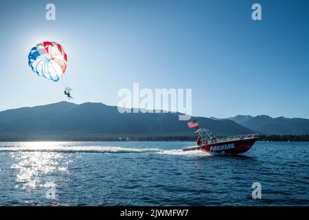 Una barca rossa taglia due parasailers in una mattinata d'estate. Foto Stock