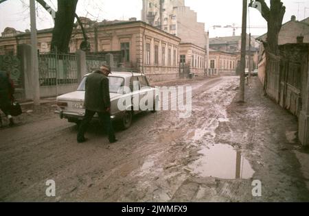 Bucarest, Romania, gennaio 1990, poche settimane dopo la caduta del comunismo. Mentre Ceausescu si concentrava sulla costruzione dei suoi progetti megalomanici, come il Centro Civico, i quartieri storici della capitale si deterioravano lentamente. Alcune case storiche nelle vicinanze del Blvd. Della Vittoria del socialismo sono state evacuate per demolizione, e a malapena sfuggite grazie alla Rivoluzione anticomunista. In questa foto, la gente cammina sulle strade fangose nel vecchio quartiere '11 Iunie'. Foto Stock