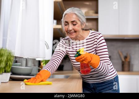 Ritratto di donna sorridente Senior che fa pulizia in cucina Foto Stock