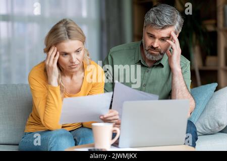 Crisi finanziaria. Pensivo Coppia di mezza età che verifica i documenti a casa Foto Stock