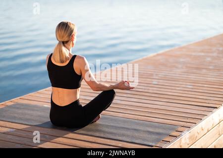 Meditazione mattutina. Calma Bionda Donna pratica Yoga all'aperto, meditando in posizione Lotus Foto Stock