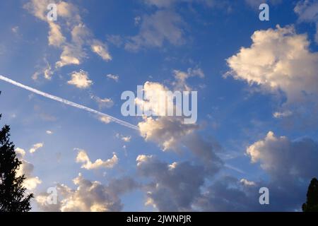 Cielo blu, nuvole soleggiate e il sentiero bianco di controtolo aereo, sfondo mattina nuvoloso, aereo che vola nelle nuvole soffici, bellezza del tempo. Foto Stock