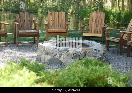 Cerchio di sedie Adirondack intorno alla fossa del fuoco Foto Stock