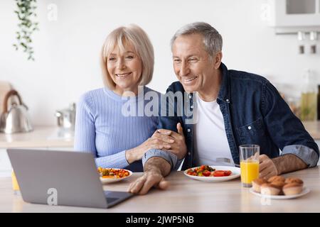 Coppia anziana che ama fare videochiamate mentre si serve la colazione Foto Stock