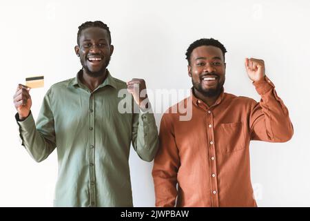 Due African Guys Holding carta di credito gesturing Sì, sfondo bianco Foto Stock