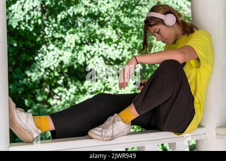 la ragazza sta riposando, ascoltando musica tramite cuffie wireless Foto Stock