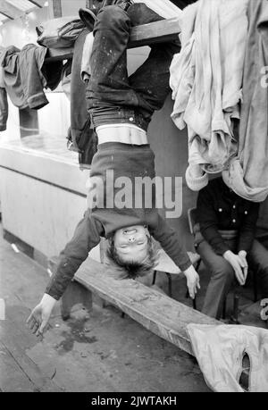 Londra, Inghilterra, circa 1967. Un giovane ragazzo e membro del Pirate Club sta penzolando capovolto a bordo di ‘Rosedale’, una chiatta in disuso che serviva da clubhouse. Il Pirate Club, un club nautico per bambini, è stato fondato nel 1966 presso Gilbey’s Wharf sul Regent’s Canal vicino a Camden, Londra. Per l’uso dei bambini erano state donate alcune piccole barche e canoe. Foto Stock