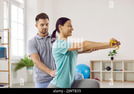 Fisioterapista maschile esperto che lavora con un giovane paziente in un centro di riabilitazione Foto Stock