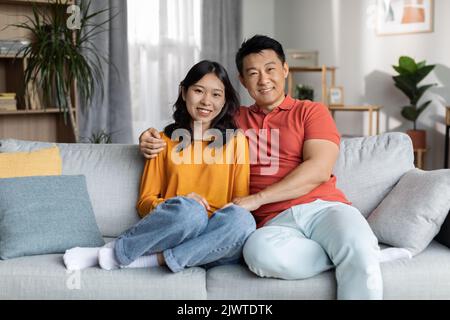 Coppia cinese amorevole che si unisce sul divano a casa Foto Stock