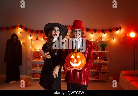 Felice giovane coppia vestita in costumi di Halloween spettrale con il loro Jack-o-lanterna Foto Stock