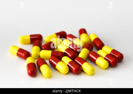 Vista ravvicinata di capsule di gelatina rosse e gialle non marcate contenenti farmaci su sfondo bianco. Nessuna gente. Foto Stock