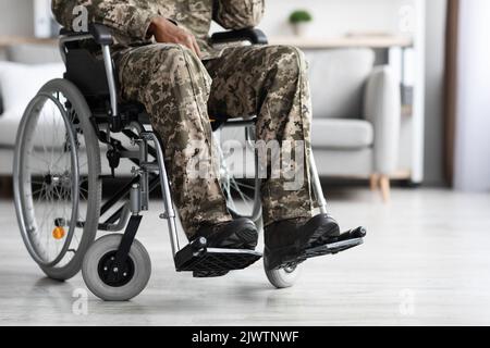 Uomo nero irriconoscibile seduto in sedia a rotelle, indossato uniforme militare Foto Stock