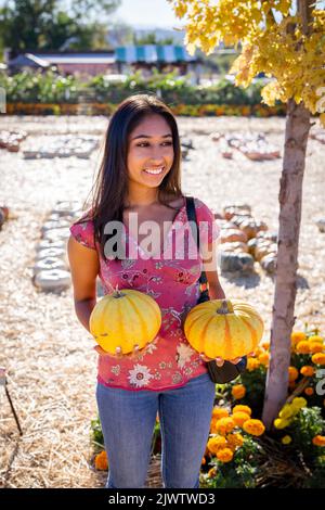 Autunno Celebrazione Ritratto di una giovane donna asiatica adatta tenendo due zucche in una fattoria Foto Stock