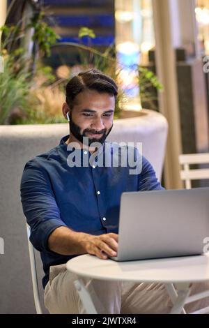 Uomo d'affari indiano che videochiama con un computer portatile nel parco notturno della città. Foto Stock