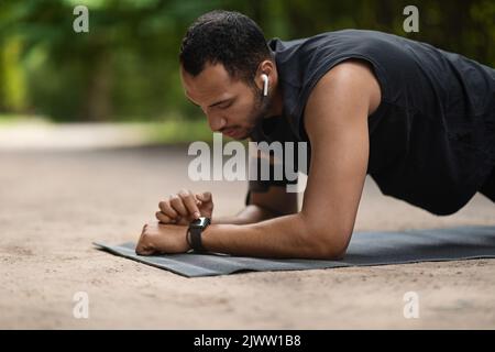 Bel giovane uomo sportivo nero ha impostato il suo fitness tracker Foto Stock