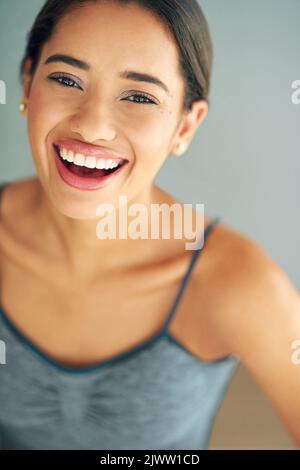 La positività può cambiare la vostra vita. Una giovane donna sportiva che si posa su uno sfondo grigio. Foto Stock