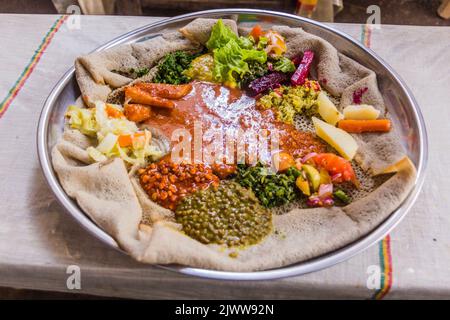 Pasto tipico in Etiopia - Beyainatu. Mearing un po' di tutto. Mix di verdure e stufati su injera flatbread. Foto Stock