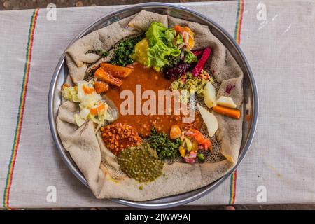 Pasto tipico in Etiopia - Beyainatu. Mearing un po' di tutto. Mix di verdure e stufati su injera flatbread. Foto Stock