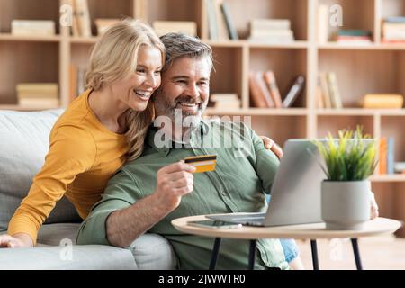 Sposi felici e maturi Prenota l'hotel online con laptop e carta di credito Foto Stock