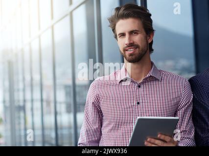 Il mio tablet è una scrivania portatile. Ritratto di un giovane uomo d'affari che utilizza un tablet digitale all'esterno di un ufficio. Foto Stock