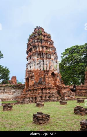 Pungente mattone rosso prang in pericolo di collasso nelle rovine a Wat Maha che, il sacro tempio reale di Ayutthaya, Thailandia Foto Stock