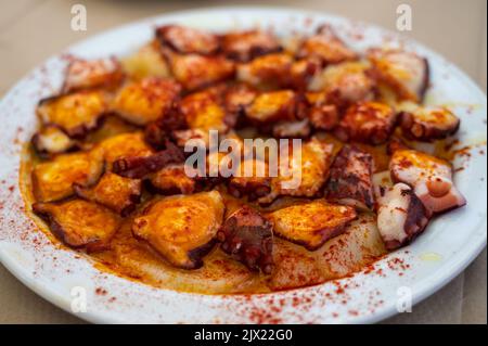 Gustosi frutti di mare, polpo alla griglia in stile galiziano con paprika pimento rosso e patate serviti nel ristorante spagnolo Foto Stock