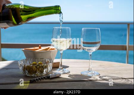 Versando di txakoli o Chacolí vino bianco leggermente frizzante molto secco prodotto nei Paesi Baschi spagnoli, servito all'aperto con vista sulla baia di Biscaglia, AT Foto Stock