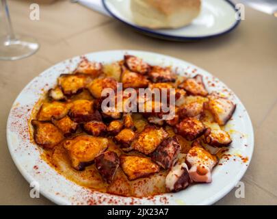 Gustosi frutti di mare, polpo alla griglia in stile galiziano con paprika pimento rosso e patate serviti nel ristorante spagnolo Foto Stock