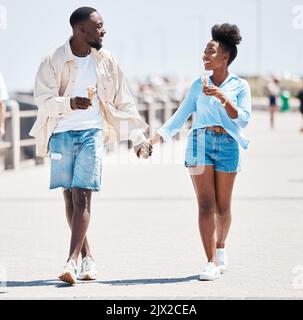 Coppia gelato, passeggiata estiva a piedi e amore, relax e spensierato divertimento insieme all'aperto. I giovani neri che tengono le mani, sorridono i partner su un Foto Stock