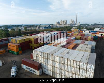 Una vista aerea sopra un terminal di container per spedizioni, con vettori come Hapag-Lloyd e Maersk container presso il cantiere di carico in un settore industriale. Foto Stock